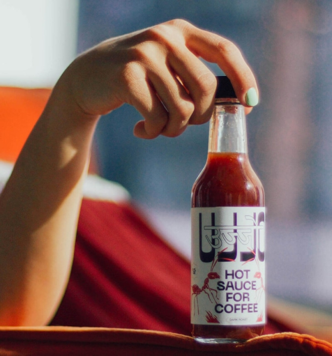 HAND HOLDING HOT SAUCE UJJO